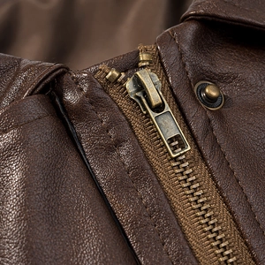 Macro shot of vintage metal zipper and button on textured brown faux leather biker jacket
