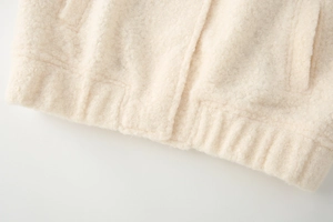 Detail view of cream sherpa jacket texture showing high-quality ribbed hem and thick wool fabric