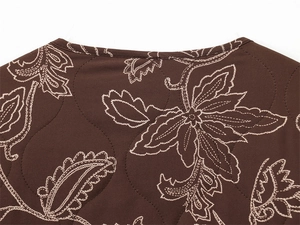 Detail of dark brown quilted jacket featuring white paisley floral embroidery and neat collar