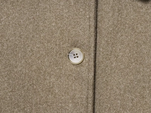 Detailed close-up of wool texture and beige button on a camel short lapel coat