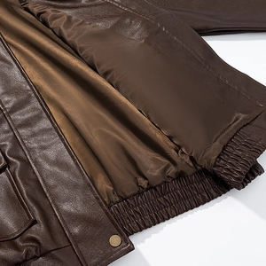 Detail view of smooth brown silk lining and textured leather edge of a biker jacket