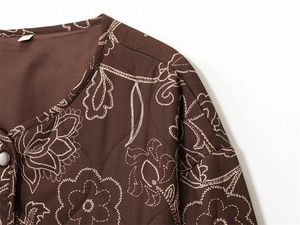 Detail of diamond-quilted brown jacket with white floral patterns and round collar