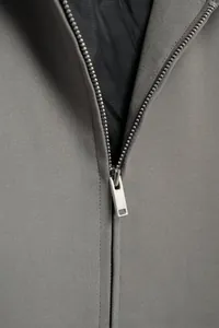 Detailed close-up of a silver metal zipper on a grey French style jacket with black lining