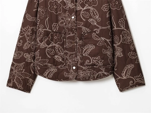 Detail of dark brown quilted jacket featuring white floral embroidery and metal buttons