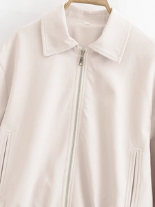 Detailed close-up of beige lapel jacket featuring silver metal zipper and smooth PU leather