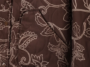 Close-up of diamond-quilted jacket with paisley floral embroidery and snap buttons