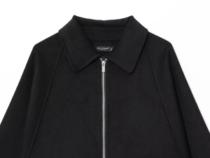 Detail of metal zipper and brand label on black wool-like jacket with turn-down collar