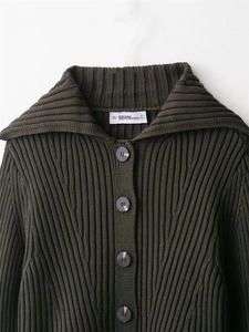 Close-up of a dark green ribbed knit cardigan featuring large lapels and tortoise buttons