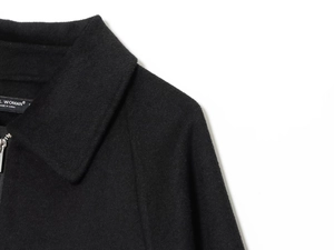 Close-up of black wool jacket collar showing silver zipper and brand inner label
