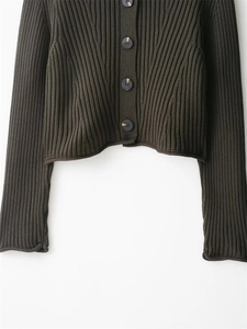 Close-up of olive green ribbed knit cardigan featuring large marble-textured buttons
