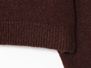 Close-up of dark brown knitted fabric with soft wool texture and ribbed cuffs detail