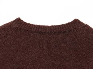 Macro detail of the ribbed crew neck and textured knit fabric on dark brown sweater