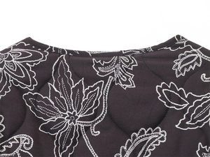 Detail of black quilted jacket featuring white bohemian floral patterns and round stitching