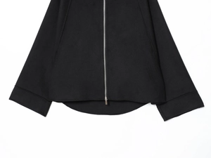 Detail of silver metal zipper and curved hem on a black soft casual jacket