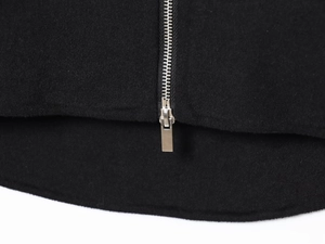Macro view of a metallic silver zipper and rectangular slider on black wool coat fabric