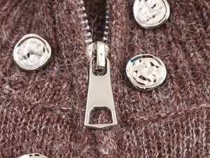 Detailed close-up of dark coffee knit fabric with silver zipper and metallic buttons