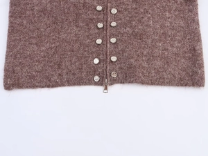 Detailed close-up of brown knit cardigan with decorative silver buttons and metal zipper