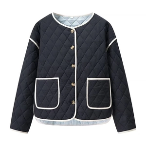 Detail of diamond quilted jacket featuring contrast white piping and striped lining