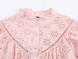 Detail of pink eyelet blouse with sun flower embroidery and ruffle stand collar