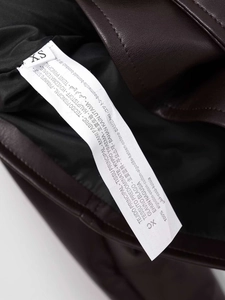 Détail de l'étiquette de lavage sur veste en cuir marron, taille XS et 100% coton