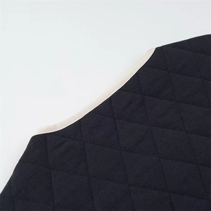 Detailed macro view of black diamond quilted fabric with contrasting beige edge piping