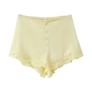 Détail du short en satin jaune pâle avec dentelle délicate et boutons décoratifs
