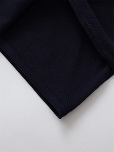Detailed macro view of the navy blue knitted sweater cuff showing fine texture and hem