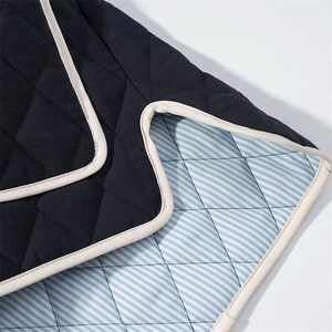 Detail of diamond quilted jacket featuring black fabric and blue striped lining with piping