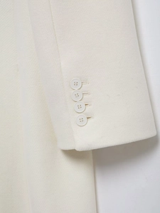 Detailed close-up of cream wool coat cuffs featuring four matched buttons and twill texture