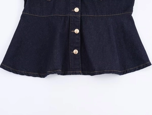 Close-up of dark blue denim jacket hem with ruffled design and gold buttons