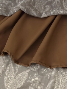 Detailed view of layered paisley print skirt with smooth brown lining and fine rolled edges