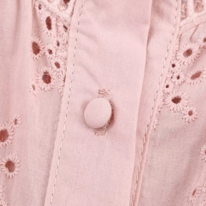 Women's soft pink blouse with delicate eyelet embroidery and fabric-covered buttons
