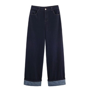 Detail of dark blue high-waisted wide leg jeans with metallic button and wide cuffed hems