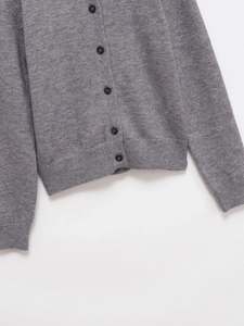 Detailed macro view of dark buttons and soft ribbed knitting texture on gray cardigan