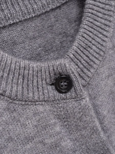 Close-up of grey knit cardigan featuring ribbed crew neck and fine texture detail