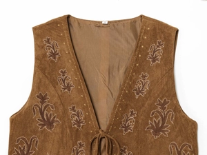 Detail of khaki faux suede vest featuring intricate brown floral embroidery and lace-up ties