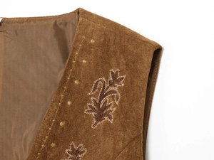 Detailed close-up of floral embroidery on a brown faux suede vest shoulder area