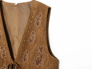 Close-up of brown suede vest featuring floral embroidery, tie front, and S-size label