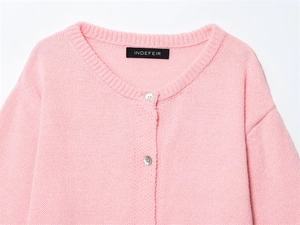 Detail of pink knit cardigan with round neck and pearlescent buttons on soft fabric