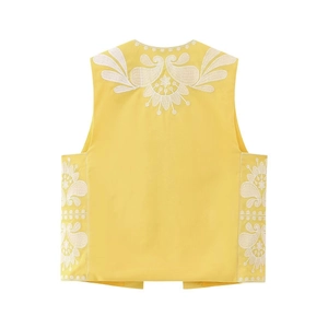 Detail of white floral embroidery on a yellow ethnic waistcoat with open front design