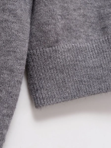 Detailed close-up of premium gray knit cardigan showing ribbed cuffs and wool texture
