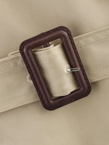 Détail de la boucle de ceinture de trench-coat kaki en résine marron avec ardillon argent