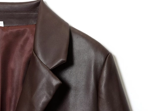 Détail du revers d'une veste en cuir marron foncé avec grain fin et coutures d'épaule