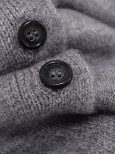 Macro shot of black resin buttons and soft grey knit texture on a luxury cardigan