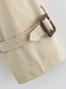 Détail macro de la sangle de manche d'un trench kaki clair avec boucle en résine