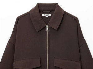 Macro detail of dark brown jacket with metal zipper and symmetrical flap pockets