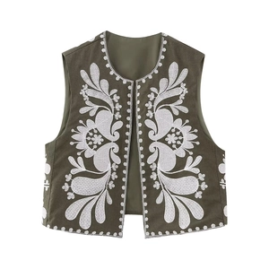 Detailed embroidery on a green bohemian vest featuring white floral patterns and sharp texture