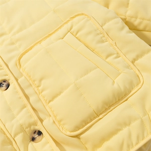 Detailed close-up of lemon yellow quilted jacket with diamond stitching and tortoiseshell buttons