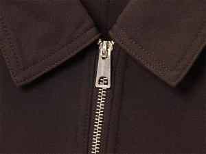 Detailed close-up of dark brown jacket collar and premium light gold metal zipper