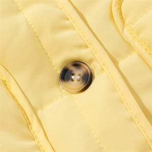 Detailed macro view of high-quality light yellow fabric with a dark marbled button finish